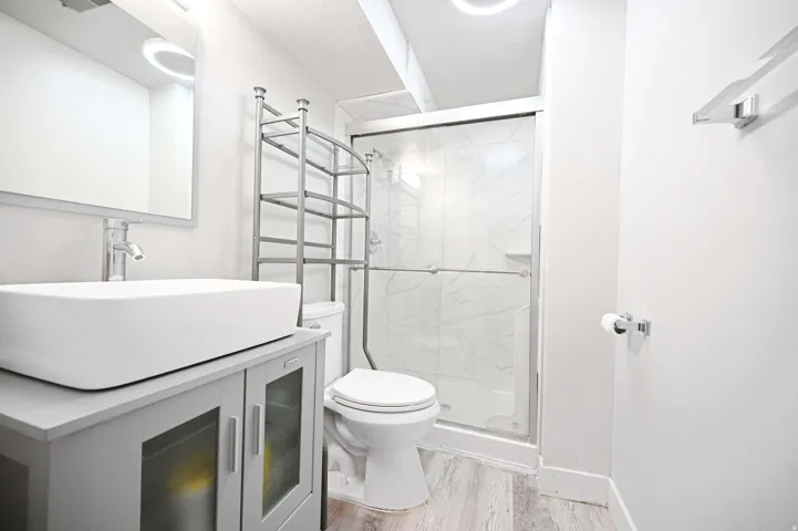 Modern bathroom featuring a glass-enclosed shower, white ceramic toilet, and a vanity with a rectangular vessel sink and chrome fixtures