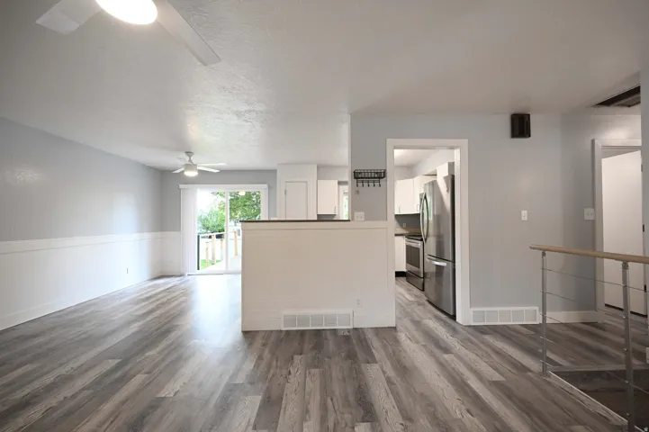 Wood-finish flooring, half-wall wainscoting, and a ceiling fan create a comfortable atmosphere