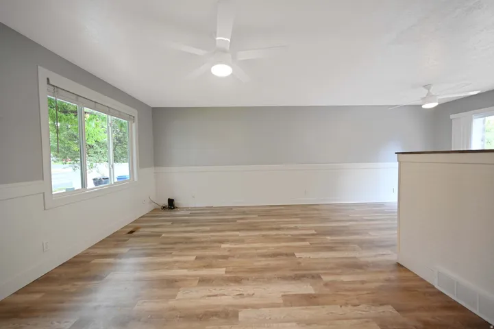 Spacious interior featuring wood-finish flooring, white wainscoting, and large windows