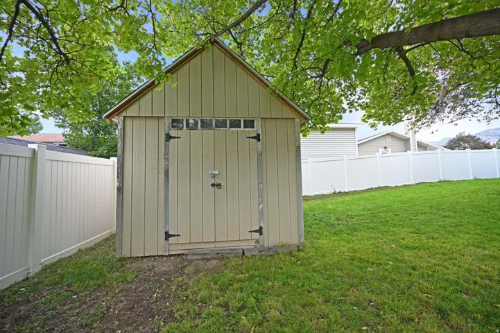 Board and batten storage shed with a gable roof, double doors, transom windows, and black hardware