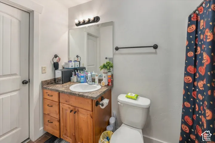 Wood-finish vanity with a built-in sink, speckled countertop, and wall-mounted light fixture