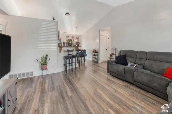 Vaulted ceilings, wood-finish flooring, half-wall room divider, and recessed lighting