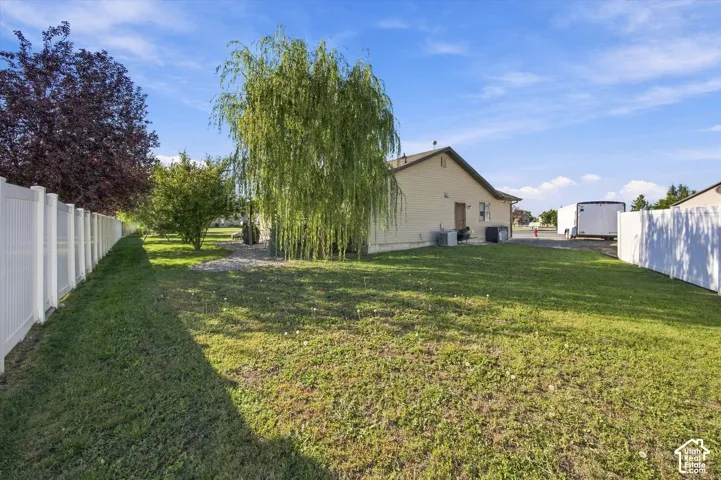 Expansive yard with green lawn, mature trees, and privacy fencing