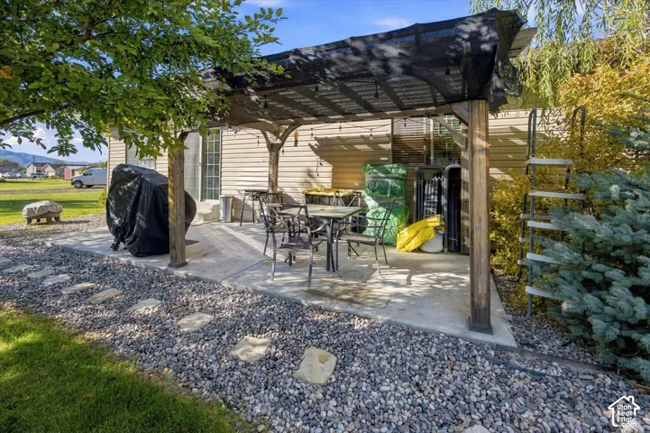 Concrete patio featuring a wood pergola with shade covering, surrounded by decorative stone and a stepping stone path