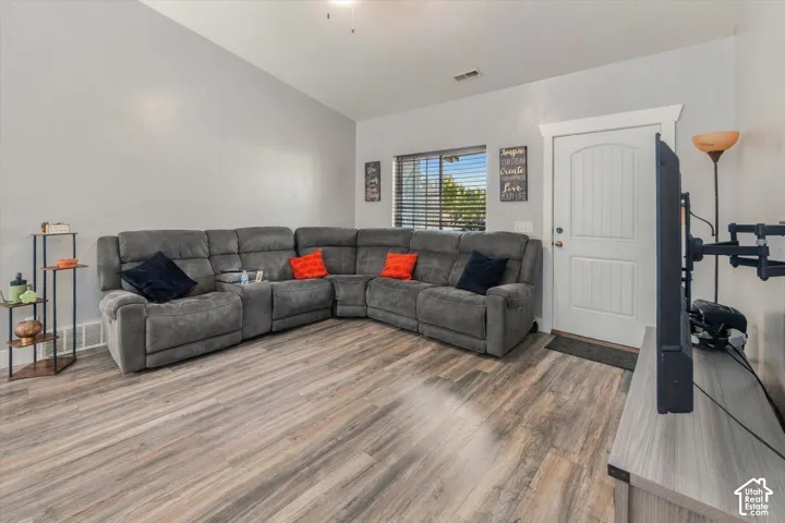 Vaulted ceilings, wood-finish flooring, white paneled door, window with horizontal blinds, ceiling fan