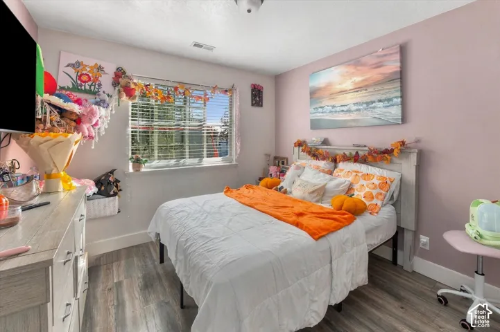 Wood-finish flooring, white trim, and a window with blinds