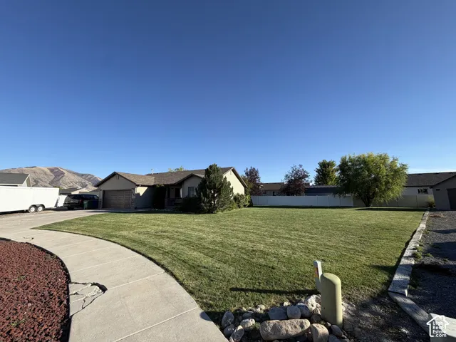 Single-story residence featuring an attached garage, a spacious front lawn, and a paved driveway