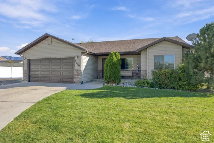 Single-story residence featuring a two-car garage, stone accents, and a well-maintained lawn