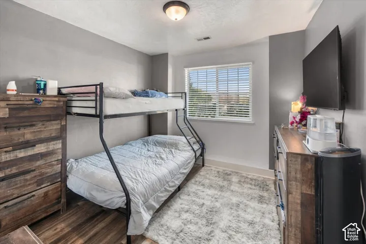 Window with blinds, wood-finish flooring, two-tone wall paint, and a semi-flush mount ceiling light