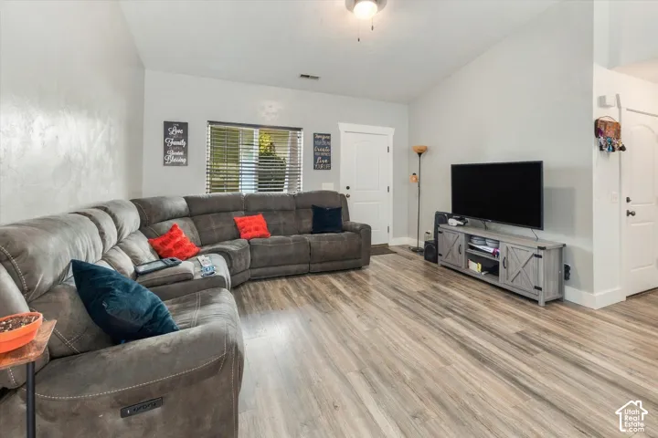 Vaulted ceiling, wood-finish flooring, white paneled doors, recessed lighting, and a large window with blinds