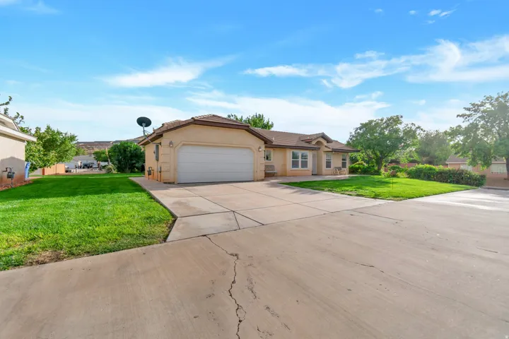 Single-story stucco exterior with an attached garage, concrete driveway, and front lawn