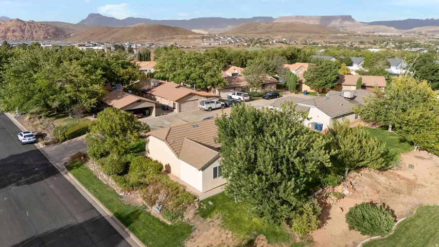 Residential property featuring a tile roof, mature landscaping, and an attached garage