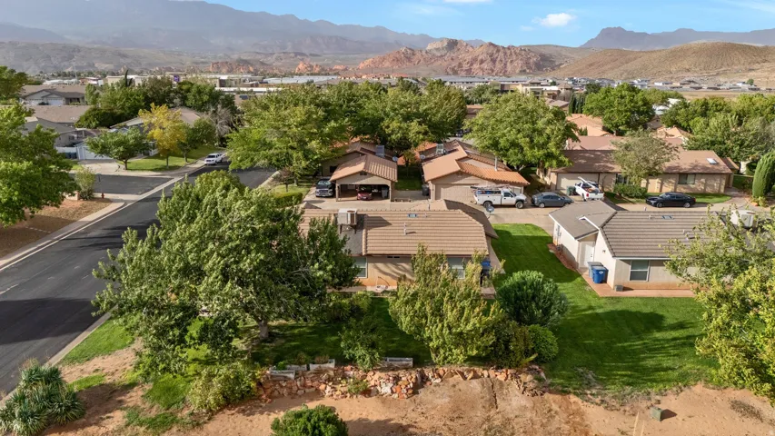 Residential neighborhood with mature trees and paved streets, framed by distant mountains