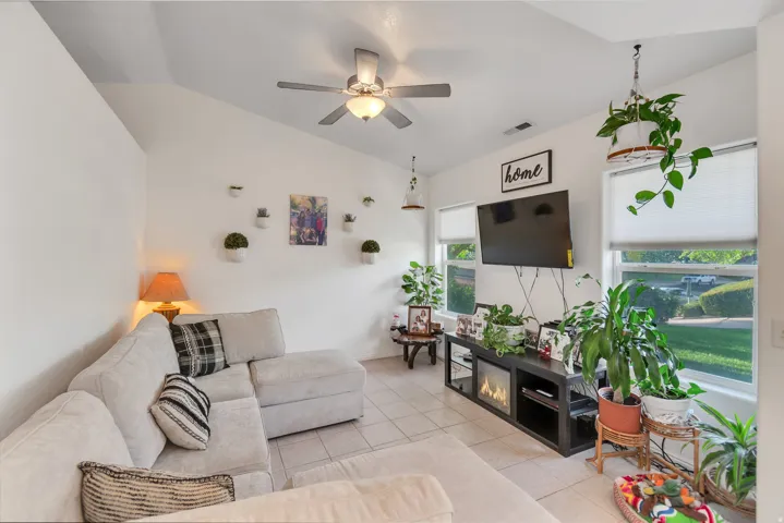 Vaulted ceiling with a ceiling fan, recessed lighting, tile flooring, and multiple windows
