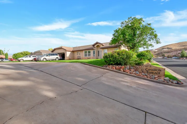 Single-story residence featuring an attached garage, paved driveway, and established landscaping