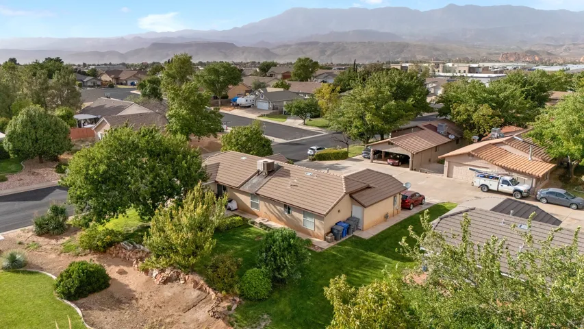 Expansive residential lot featuring mature trees, a manicured lawn, and mountain scenery
