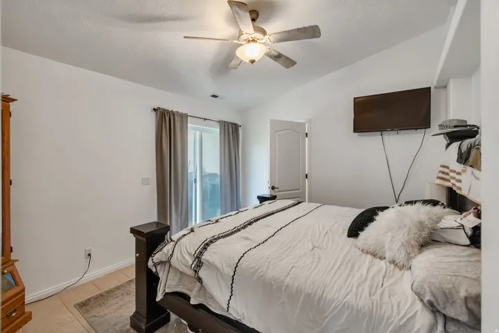 Vaulted ceiling with a ceiling fan, sliding glass door, interior door with a paneled design, and tile flooring