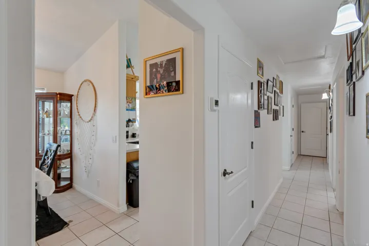 Hallway with light-colored tile flooring, white walls, and multiple paneled doors