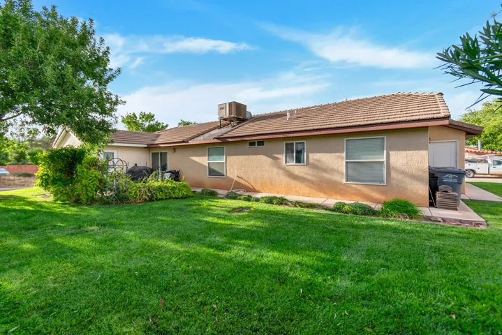 Expansive lawn, stucco exterior, tile roofing, mature trees, and concrete patio