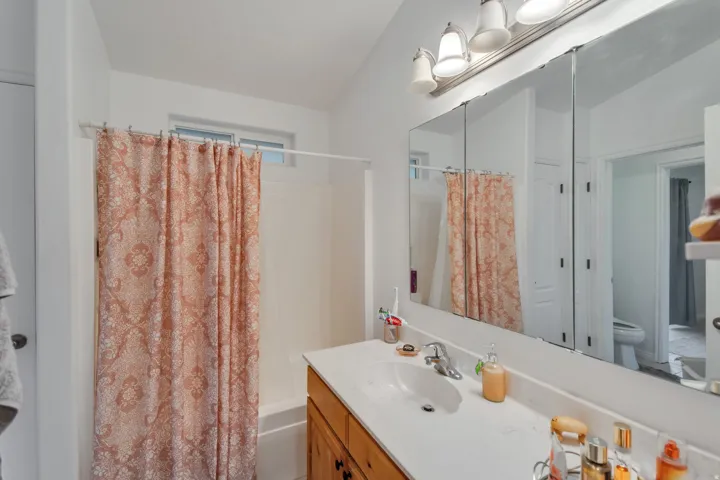 White vanity countertop with an integrated sink, polished chrome faucet, and wood-finish cabinetry