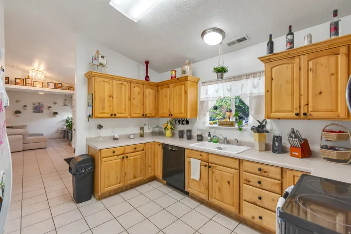 Light wood-finish cabinetry, white countertops, built-in dishwasher, and a white sink