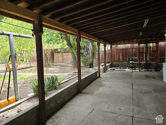 Expansive covered patio featuring a concrete surface, exposed wood beam ceiling, and integrated concrete planters
