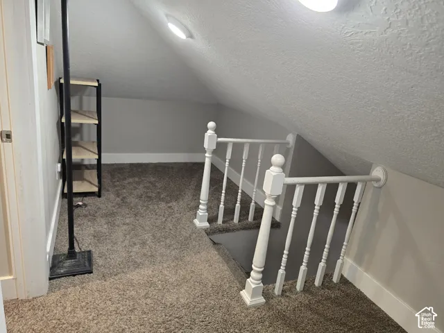 Carpeted loft area featuring a white spindle railing and sloped ceilings with recessed lighting