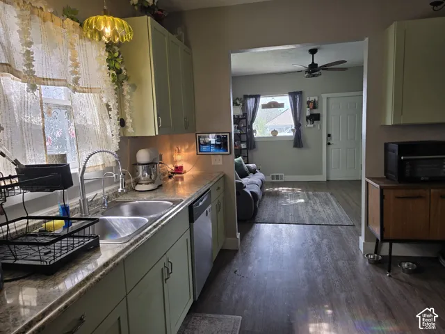 Light-toned kitchen cabinetry with a double basin stainless steel sink, a pull-down faucet, and a built-in dishwasher