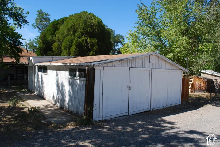 Outbuilding with double doors, multiple windows, and a shingle roof