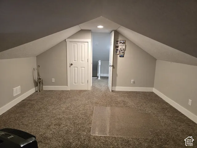 Carpeted room with sloped ceilings and white trim