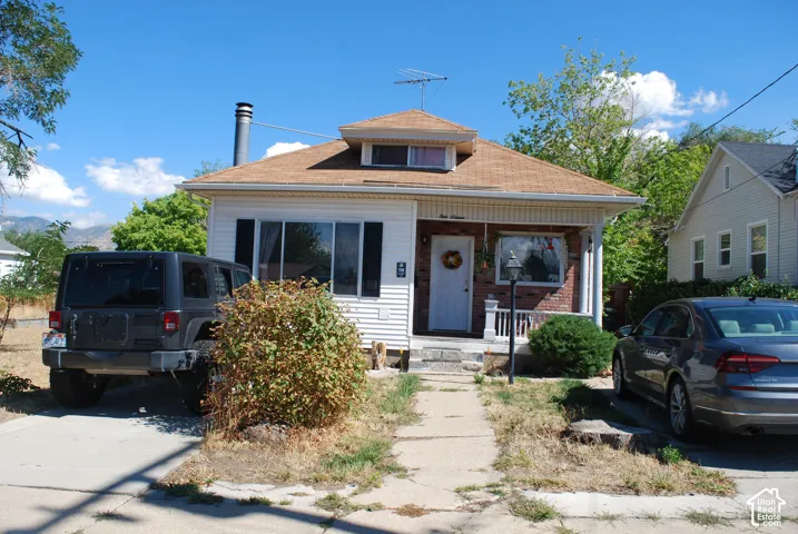 White siding exterior with a brown shingle roof and a covered porch