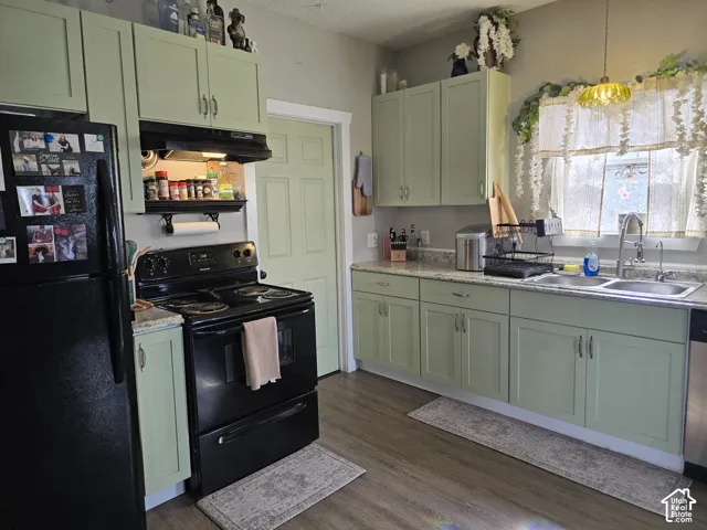 Kitchen featuring light green cabinetry, granite-finish countertops, stainless steel sink, and wood-finish flooring