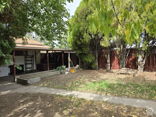 Covered patio area with a concrete walkway and surrounding mature trees