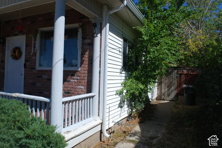 Front porch with brick facade detailing, white siding, and a privacy fence