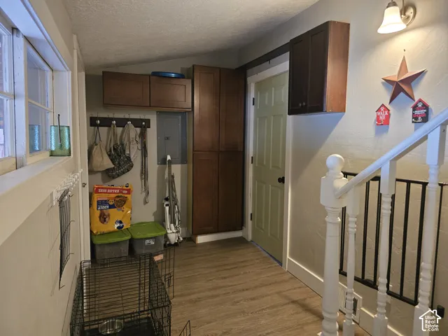 Wood-finish flooring, built-in cabinetry, interior door with paneling, white banister with black spindles, and a wall-mounted light fixture