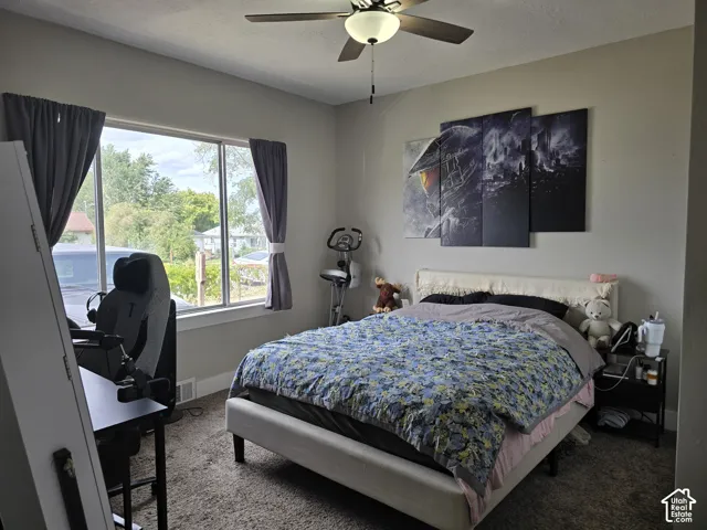 Neutral wall color, ceiling fan with integrated lighting, window with white trim, and textured carpeting