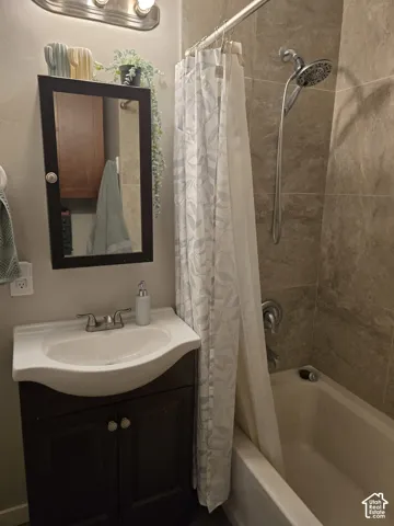 Bathroom featuring a vanity with an integrated sink, a medicine cabinet, a full bathtub with shower, and tile surround