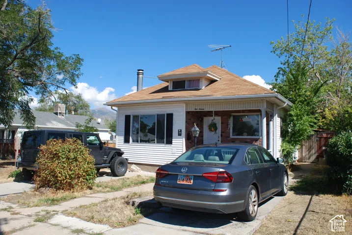 White siding exterior with brick accents, multi-pane windows, and a dormer
