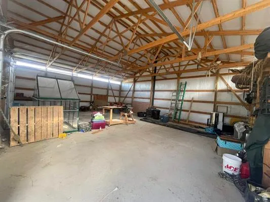 Spacious interior with exposed wood beam ceiling, concrete flooring, and metal overhead door track system
