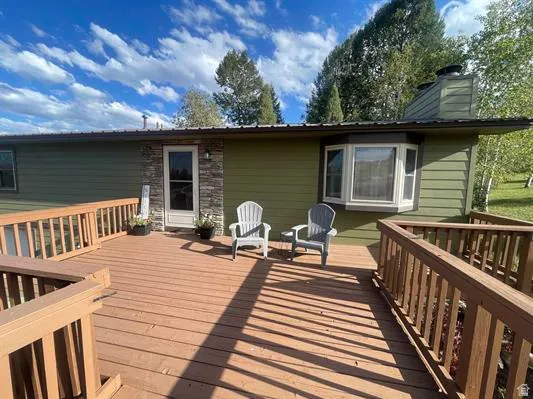 Expansive wood deck with railing, featuring a bay window, a stone facade accent, and a metal roof