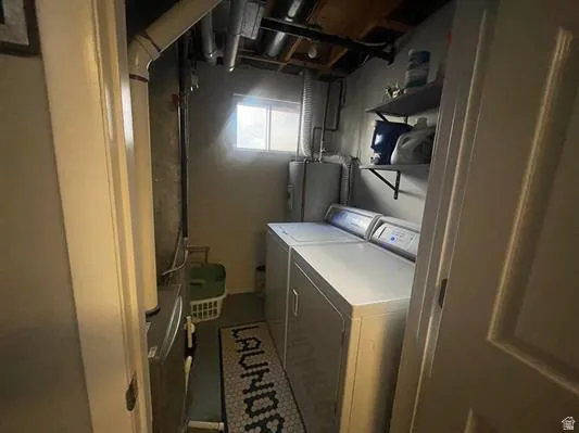 Dedicated laundry area featuring a window, overhead exposed ductwork, and wall-mounted shelving