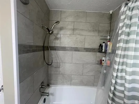 Bathtub with integrated shower, subway tile surround, accent tile band, and a brushed nickel shower head with handheld attachment