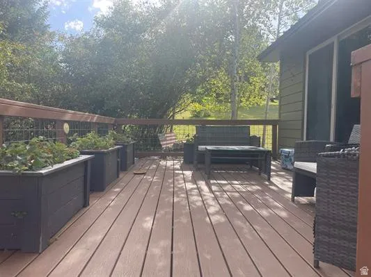 Expansive wood-finish deck with a wire railing system, adjacent to a structure with siding and a sliding glass door