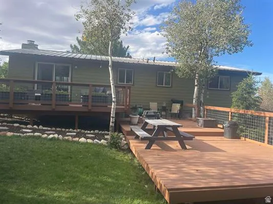 Expansive multi-level wood deck, metal roof, green siding, sliding glass door, and integrated wire mesh railing