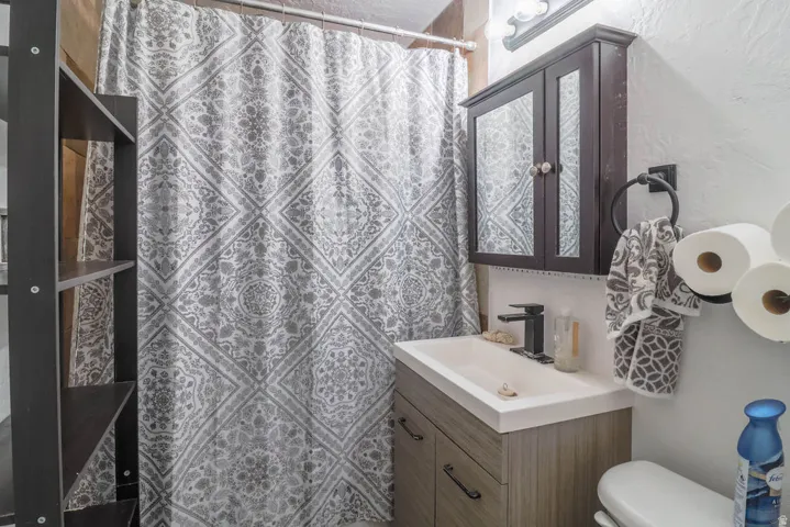 Floating vanity with integrated sink, dark wood medicine cabinet, matte black faucet, and wall-mounted shelving