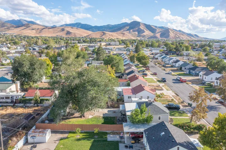 Residential street with established homes, mature trees, and mountainous terrain in the background