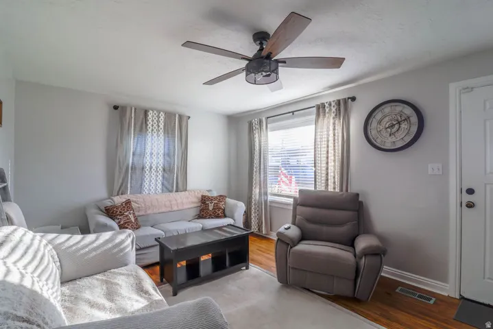 Wood-finish flooring, ceiling fan with integrated lighting, and white trim