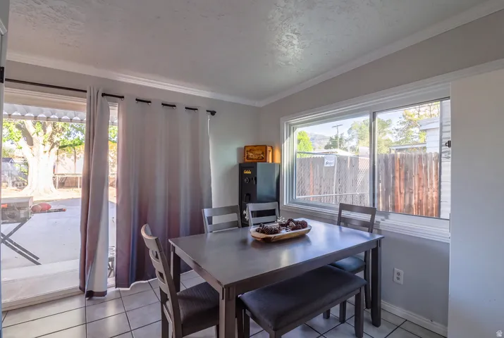 Ceramic tile flooring, crown molding, a large sliding glass door, and a spacious window