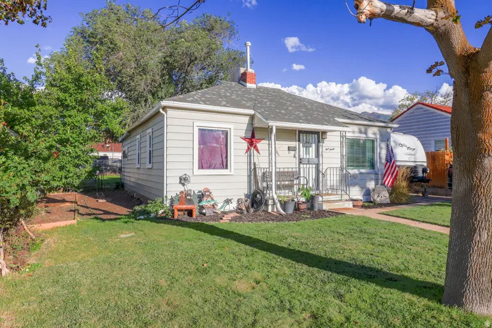 Siding exterior with a covered front porch, an asphalt shingle roof, and a mature front yard with a concrete pathway