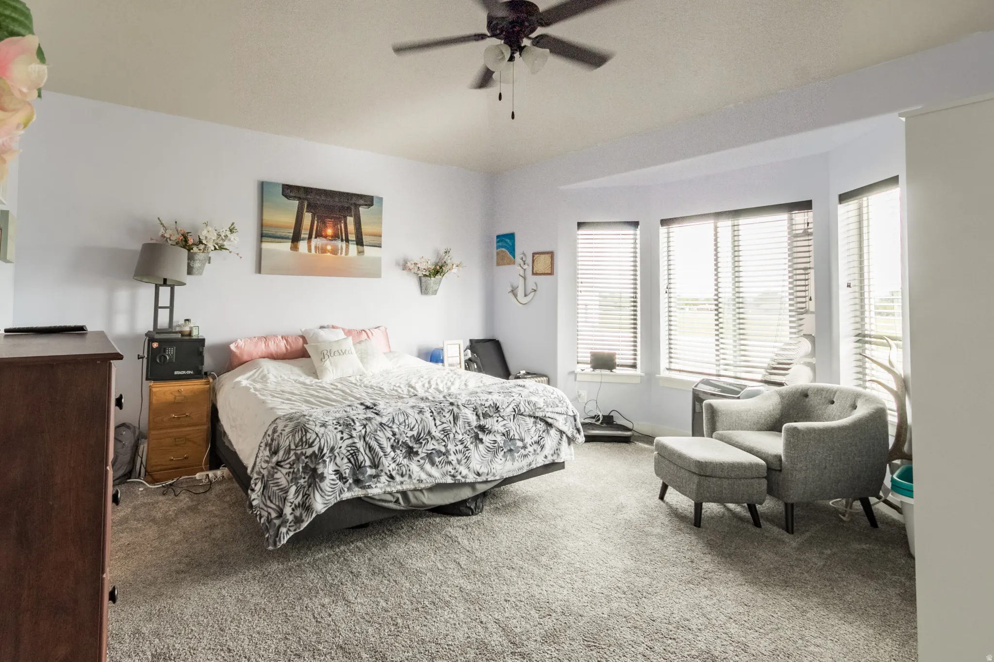 Carpeted room featuring a bay window with blinds and a ceiling fan